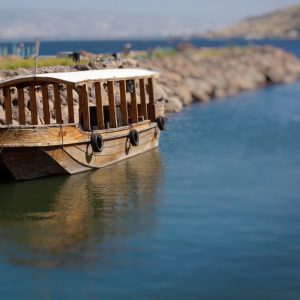 Single ancient boat on the see of galilee with reflection in the water